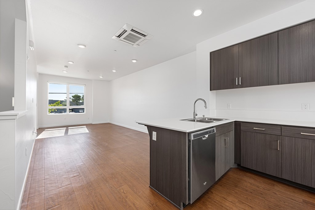 A kitchen with dark wood floors and white walls.